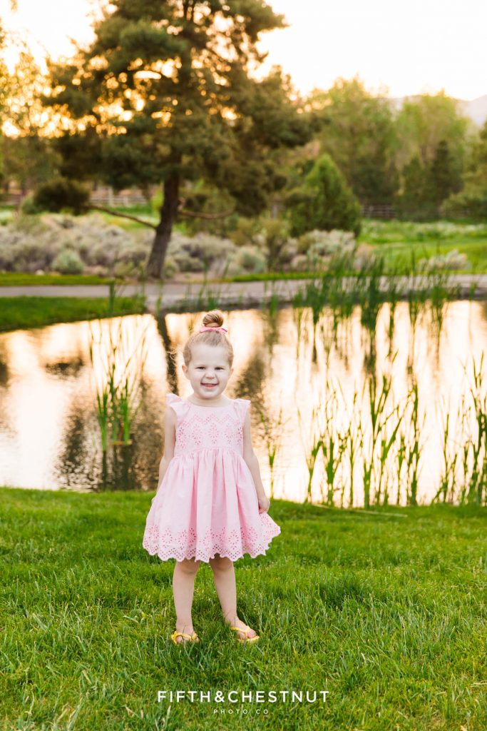 A blonde girl stands in front of a reflective pond for her spring wildflower portraits by reno child photographer (her mom)