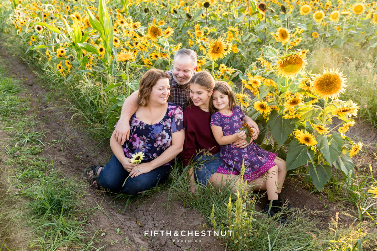 A family of four laughs with each other in a sunflower field as they enjoy their reno sunflower family photos by Reno Family Photographer Fifth and Chestnut