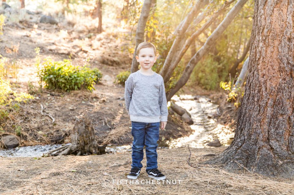 A four year old boy stands proudly in front of a creek for his reno child portraits