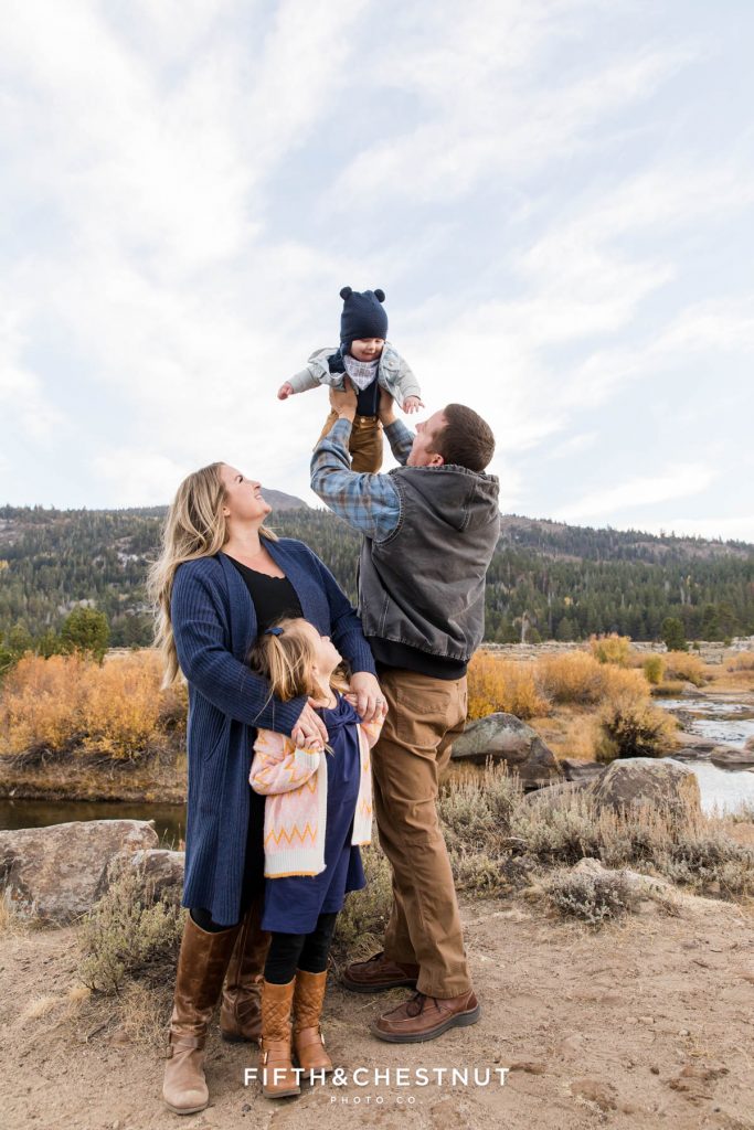 a dad hold his baby up in the air with a picturesque Hope Valley background during their Hope Valley family portraits
