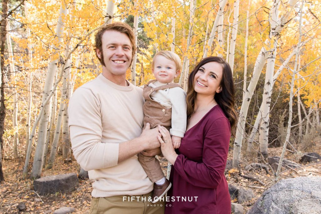 Golden Reno Fall Family Portrait of a mom wearing burgundy and a dad wearing khaki and cream with their baby boy wearing corduroy overalls and a cream shirt
