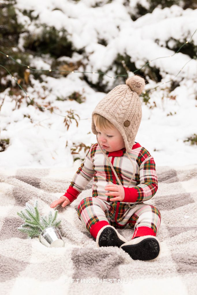 A little boy plays with a snowy tree during holiday pajama mini portraits at Callahan Park by Reno Family Photographer