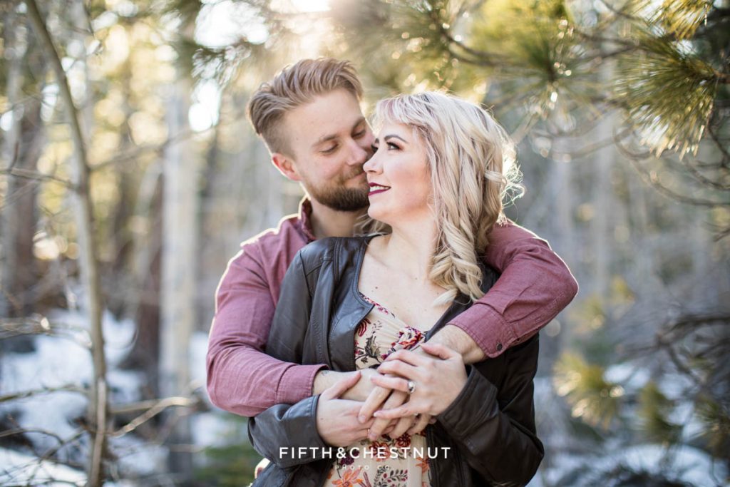 A couple snuggles in the forest during their adorable winter Reno family portraits by Reno Family Photographer