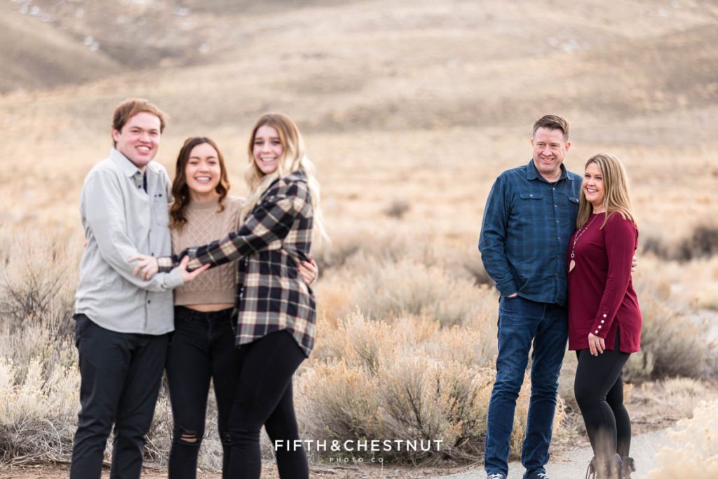 a Mom and Dad look lovingly at their grown children in the foreground during desert family portraits by Reno Family Photographer