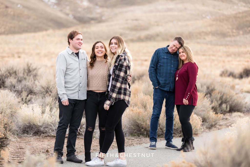 a Mom and Dad look lovingly at their grown children in the foreground during desert family portraits by Reno Family Photographer while the kids laugh