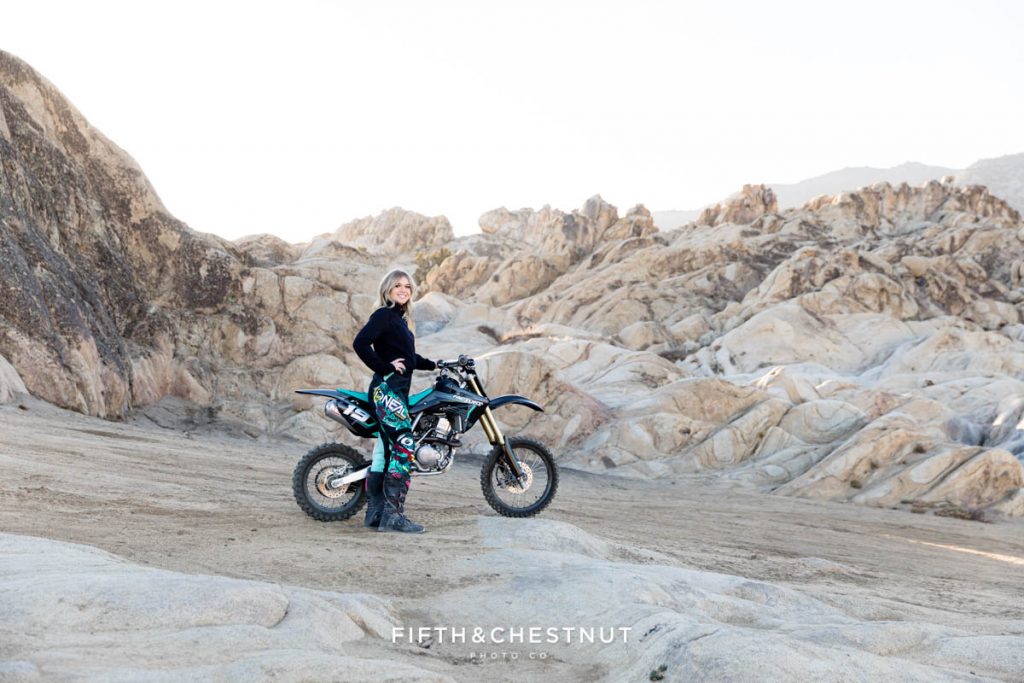 A teen posing with her dirt bike and wearing teal and pink dirt bike gear for her Magical Moon Rocks Senior Portraits by Reno Senior Photographer