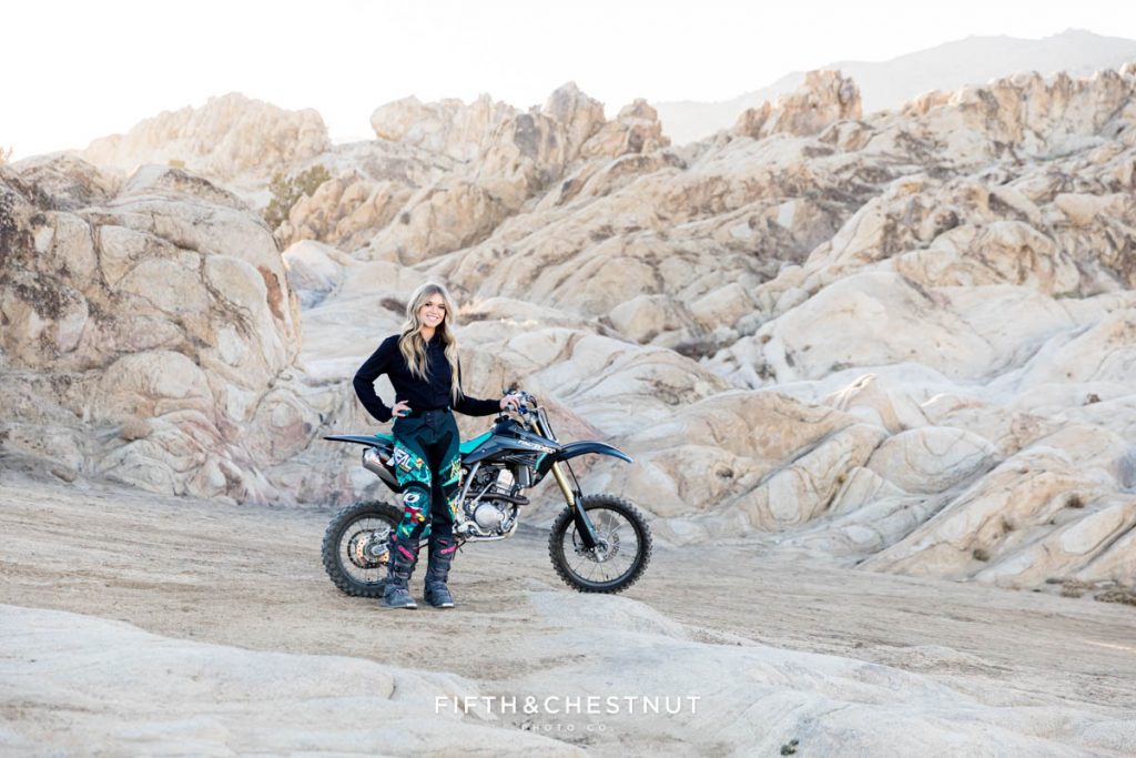 Incredible environmental senior portrait at Moon Rocks, Reno NV by Reno Senior Photographer in winter with dirt bikes and dirt bike gear with a lovely Damonte Ranch Senior!