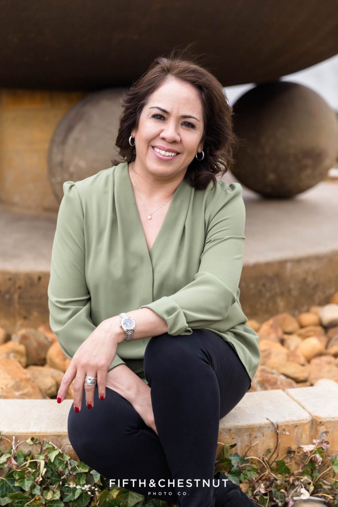 Woman sitting with her hands in her lap in front of a fountain for her early Spring Reno Headshots