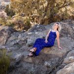 A high school senior in a blue sequin dress leans on a rock at Moon Rocks for her unique and exquisite Reno senior portraits by Reno Senior Photographer