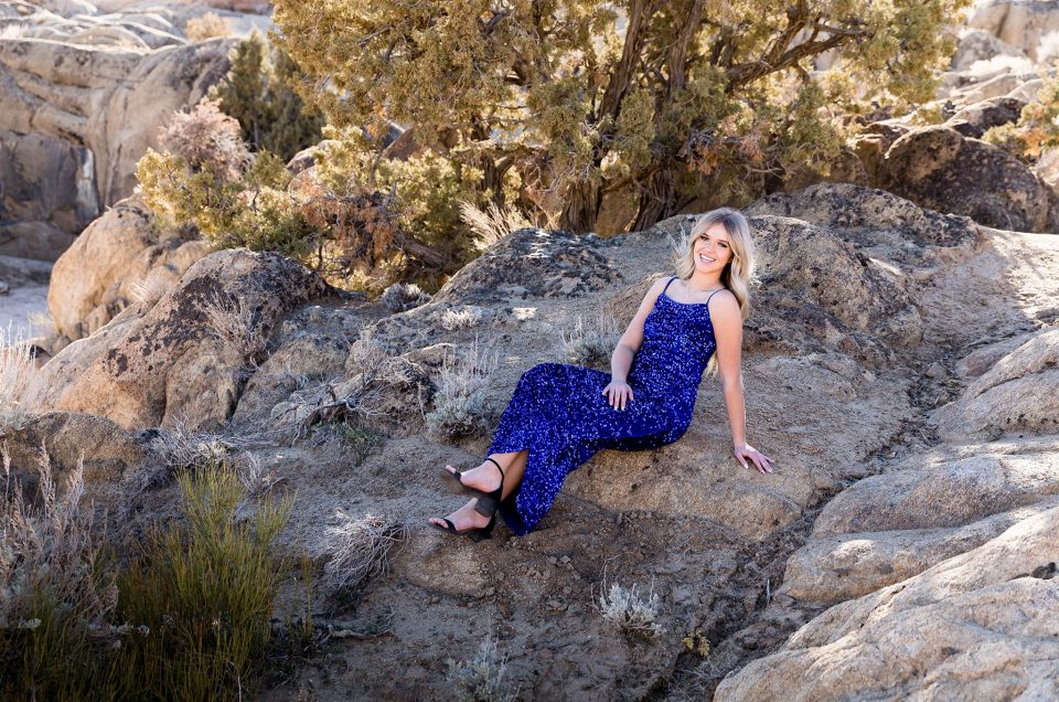 A high school senior in a blue sequin dress leans on a rock at Moon Rocks for her unique and exquisite Reno senior portraits by Reno Senior Photographer