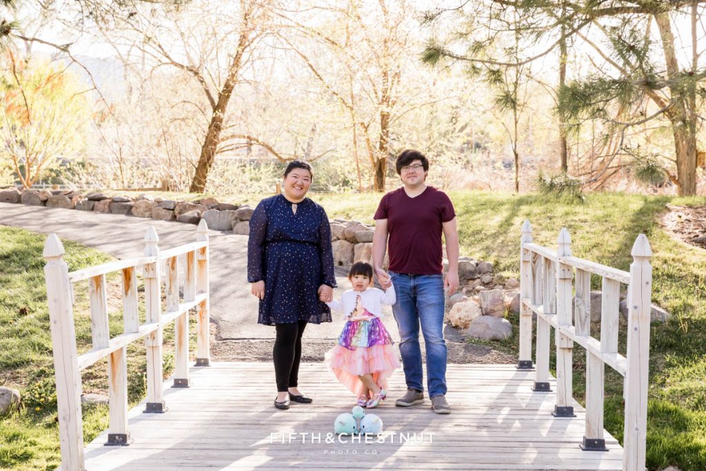 Cute portrait of a family of three with narwhal stuffed animals on a bridge for a Reno Family Portraits