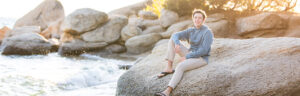 A Manogue High School Senior relaxes on a boulder in North Lake Tahoe for his Lake Tahoe Senior Portraits by Lake Tahoe Senior Photographer on a gorgeous sunny summer evening along the beach