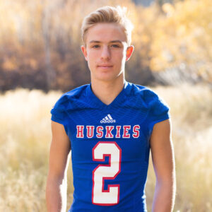 A portrait of Reno High School football player wearing his red white and blue Huskies football jersey in front of a field of fall color on Mt. Rose HWY