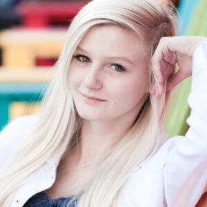 A senior portrait of a blonde Reno high school senior at the West Street Market sitting on colorful chairs
