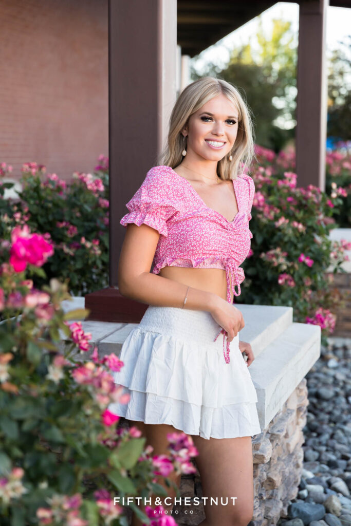 Gorgeous Reno/Tahoe Summer Senior Photos Featuring Skyler in front of pillars and rose bushes, matching with her beautiful pink patterned top.