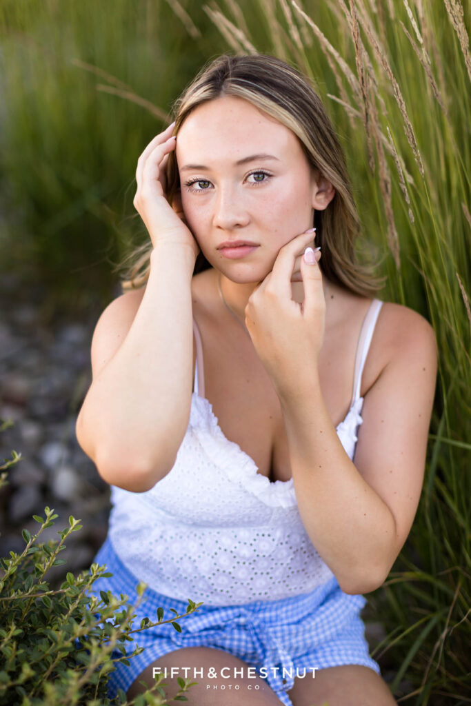 Summer Senior portraits in Sparks by Reno Senior Photographer with Payton, wearing blue gingham and a white eyelet top in the midst of tall grass.