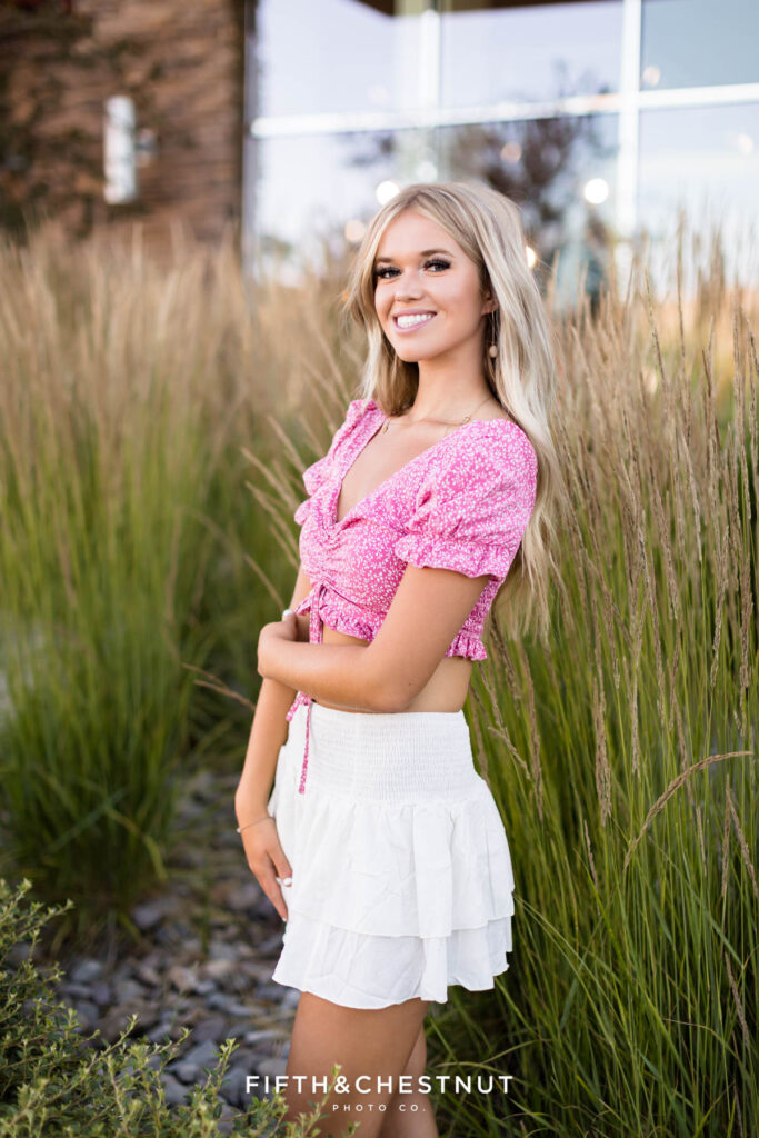 Gorgeous Reno/Tahoe Summer Senior Photos Featuring Skyler in front of tall grass and reflective windows.