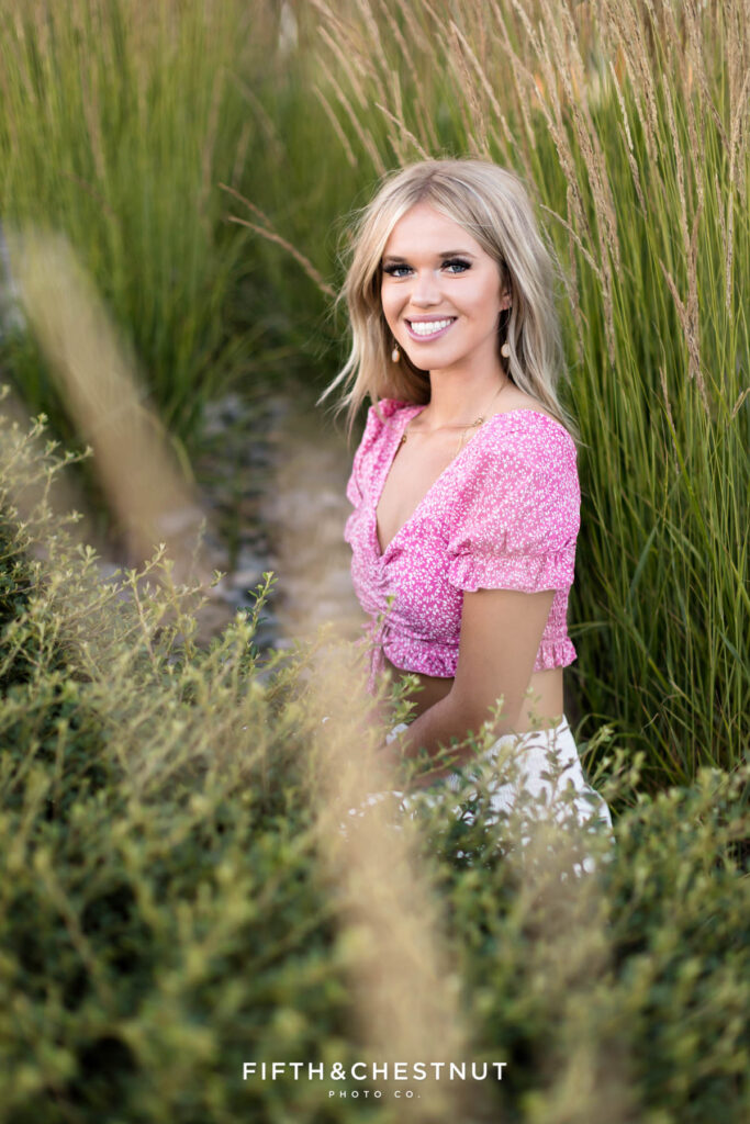 Gorgeous Reno/Tahoe Summer Senior Photos Featuring Skyler in tall grass with gravel and the wind blowing in her hair.