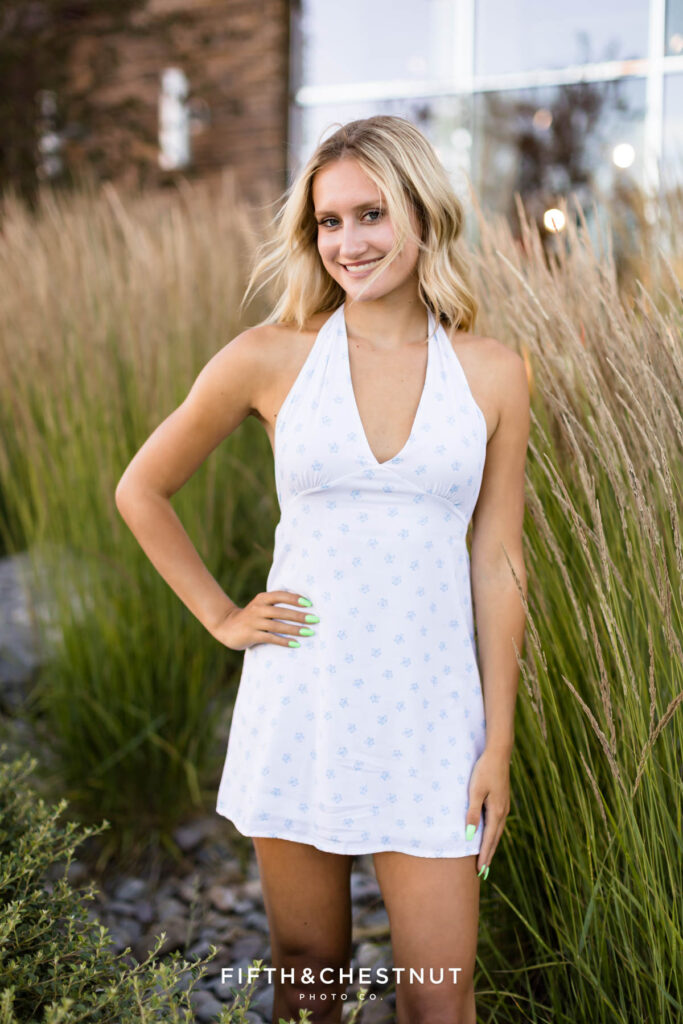 Stunning and sunny summer Reno Senior Photos of Rylan in front of tall grass and reflective windows in the background.