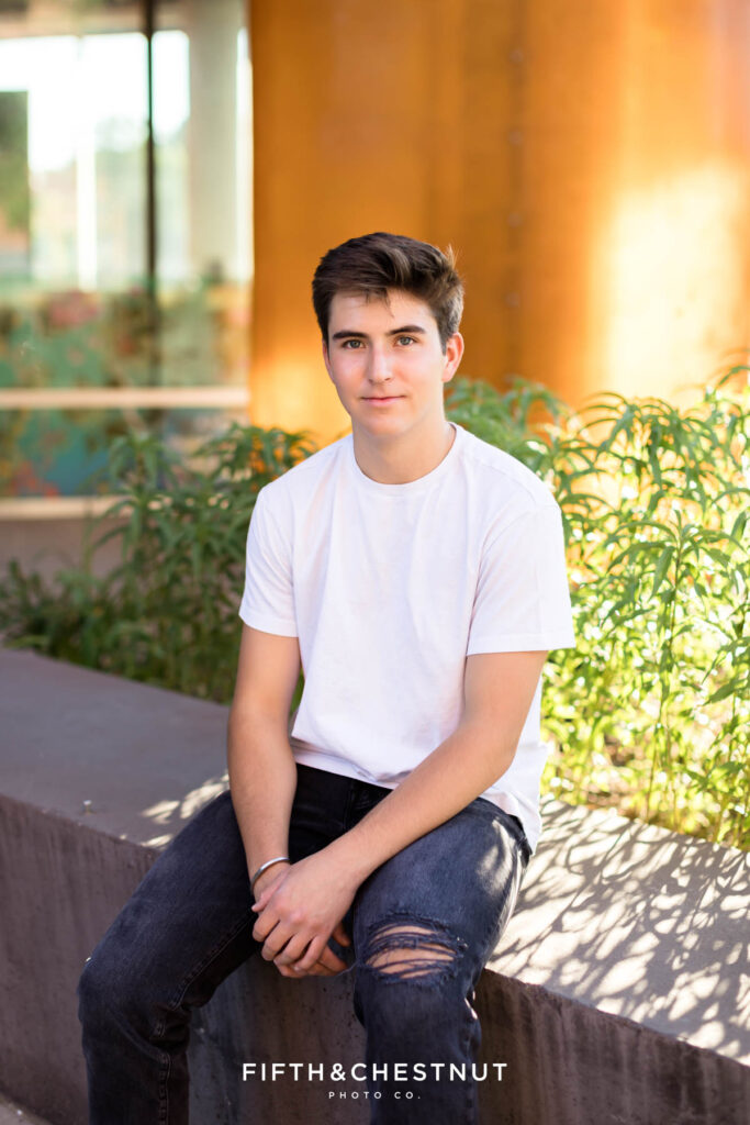 Creative Midtown Senior Portraits at the Nevada Museum of Art in Reno, NV with a senior wearing a casual white t-shirt, black jeans with a rip in the knee and white and black nike sneakers.