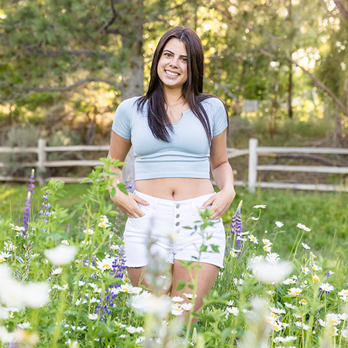 A gorgeous Carson City High School Senior standing casually in a fields of purple lupines and white daisies for a senior portrait by Reno Senior Photographer Fifth and Chestnut Photo Co.