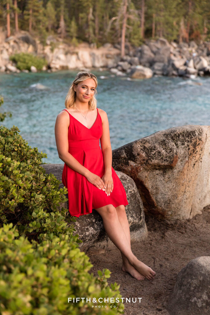 Senior basks in the sunset while the blue and emerald green waters of Lake Tahoe glimmer down below behind her for a glorious Lake Tahoe Senior Portrait by Lake Tahoe Senior Photographer.