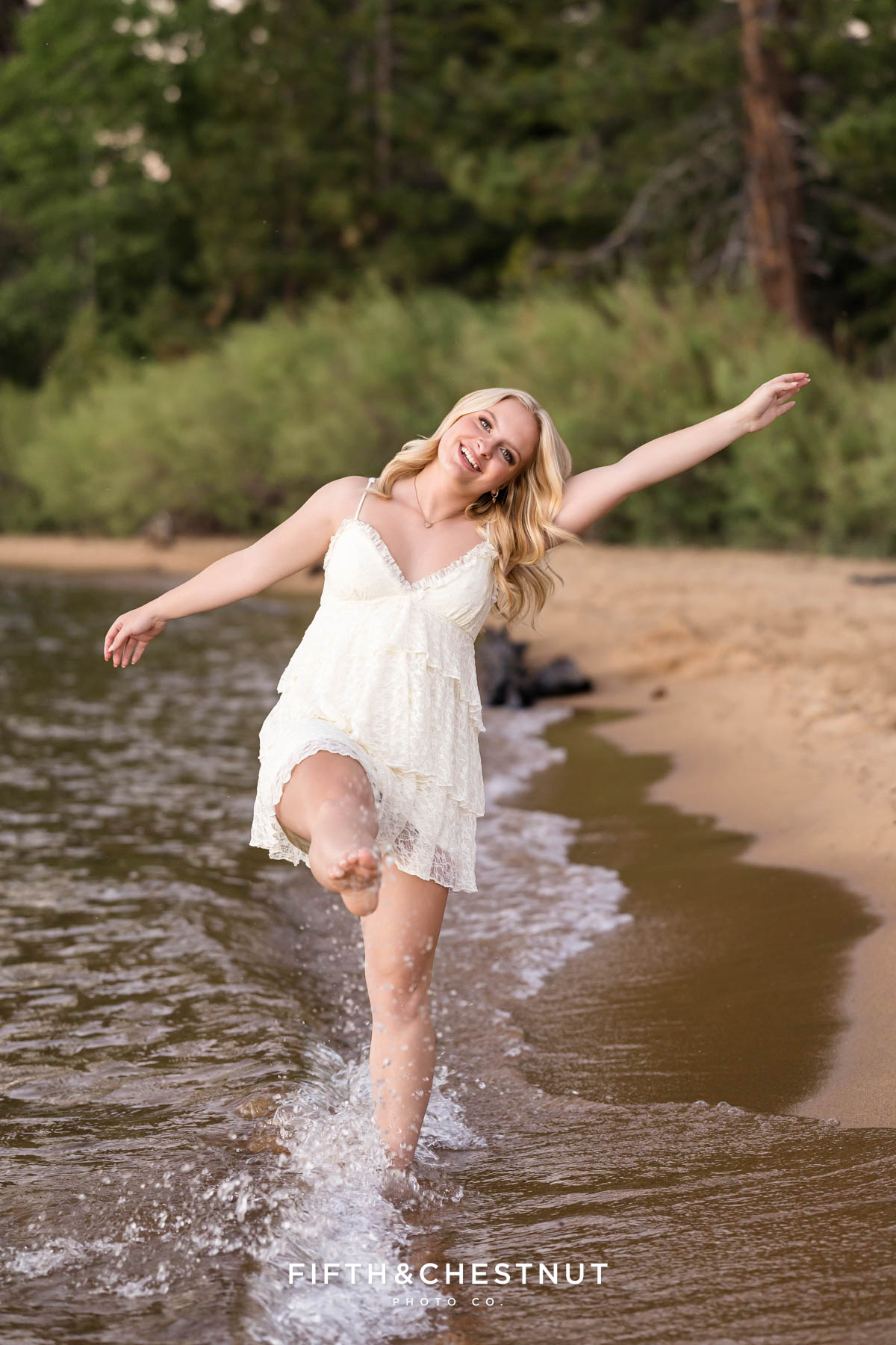 Reno High School Senior walking down the Tahoe shoreline kicking water up at the camera