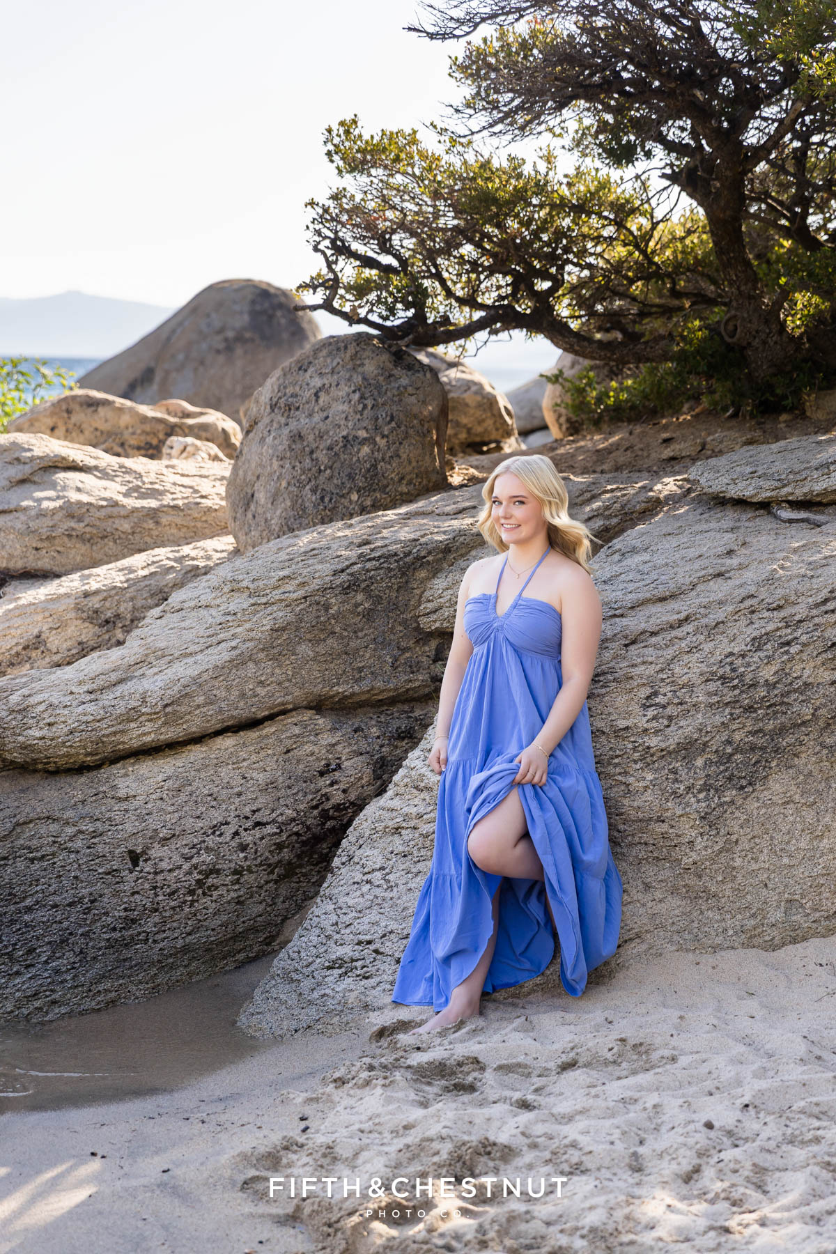 Bishop Manogue Senior in a flowing blue dress standing by large granite boulders in Tahoe