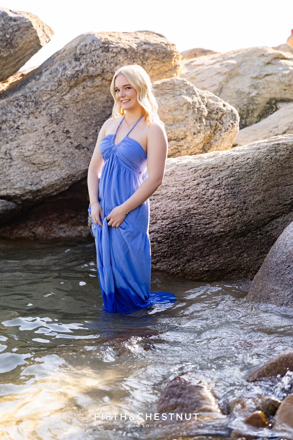 Bishop Manogue Senior in a flowing blue dress standing in Lake Tahoe with her dress floating in the water below as she poses for her senior portraits with Reno Senior Photographer