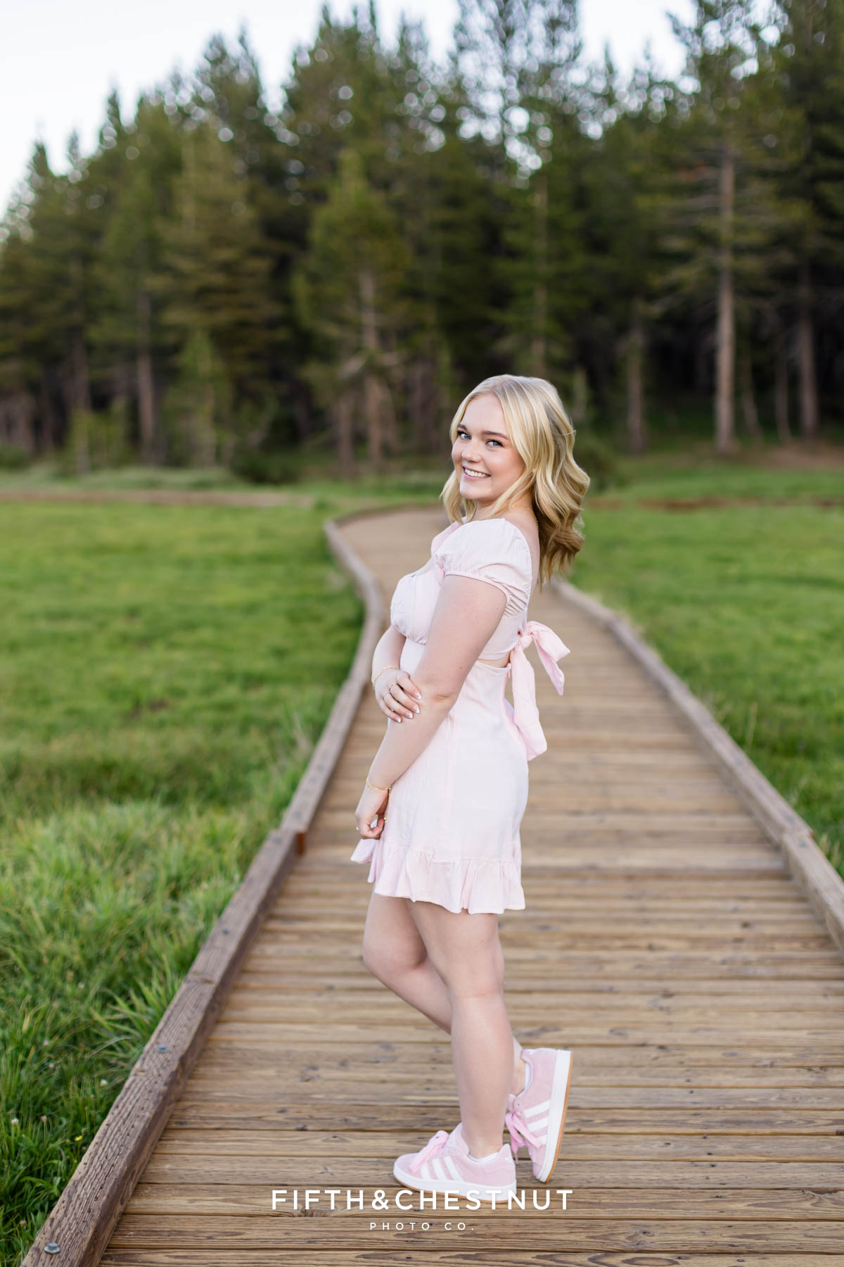 Bishop Manogue Senior smiling in a pink dress on the boardwalk in the Tahoe Meadows