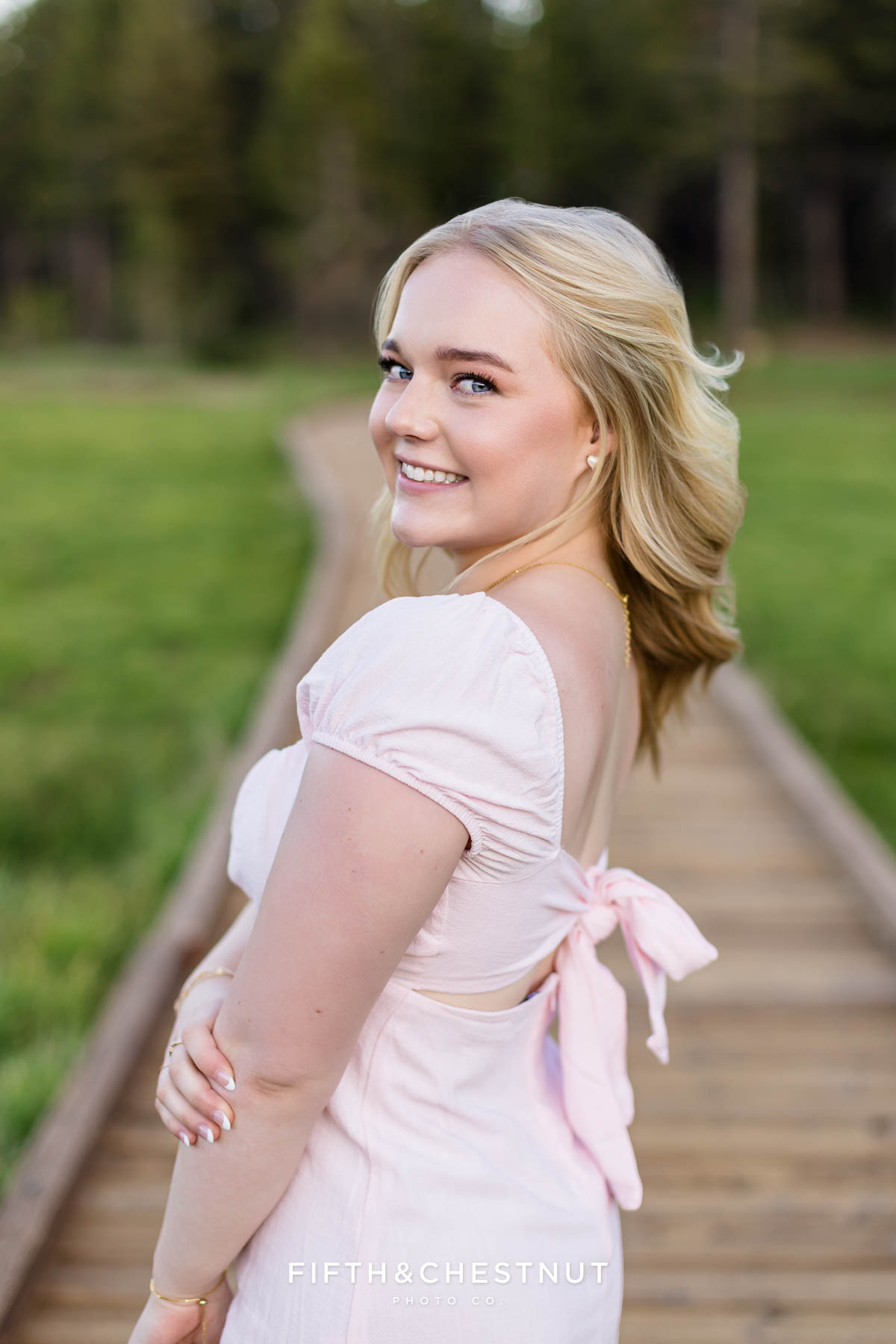 Bishop Manogue Senior smiling in a pink dress on the boardwalk in the Tahoe Meadows