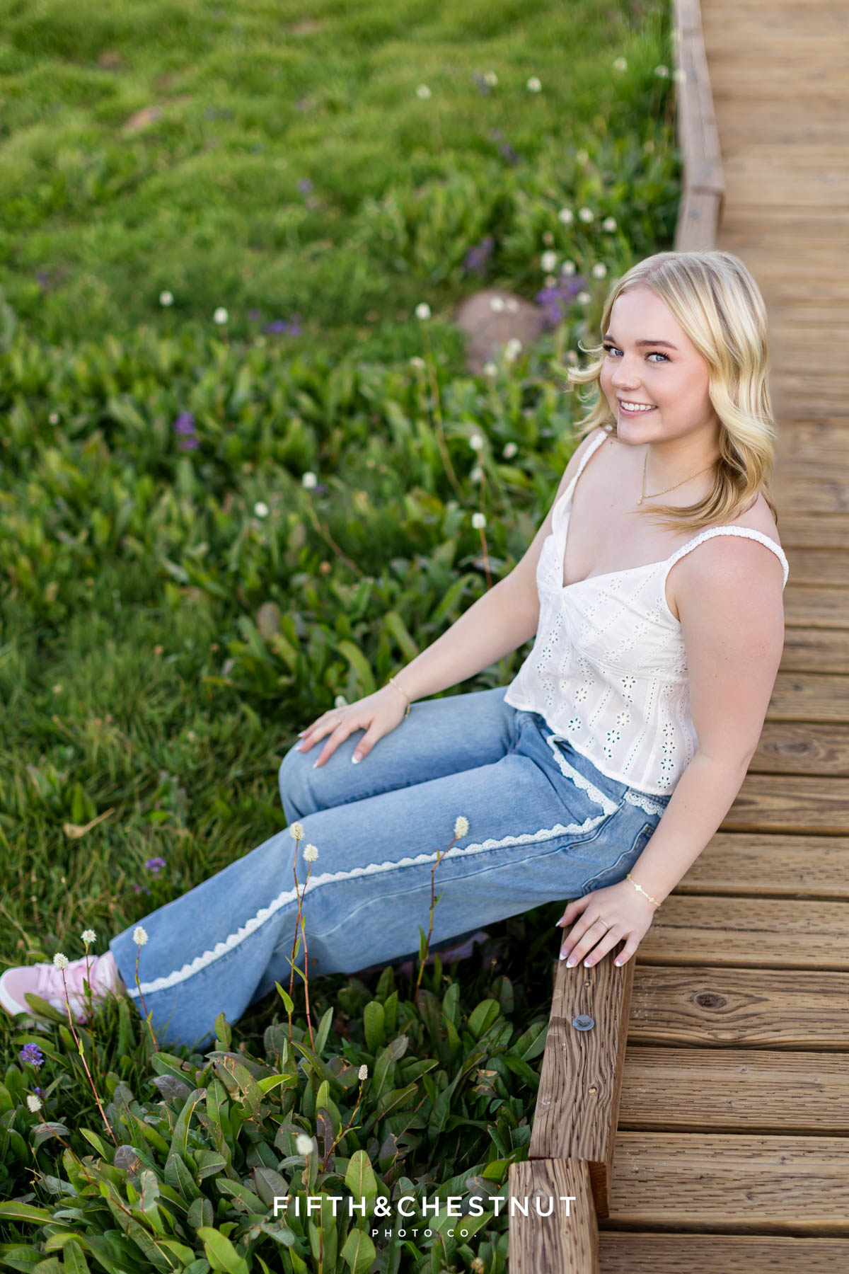 Bishop Manogue Senior seated on a wooden boardwalk in casual outfit for senior portraits