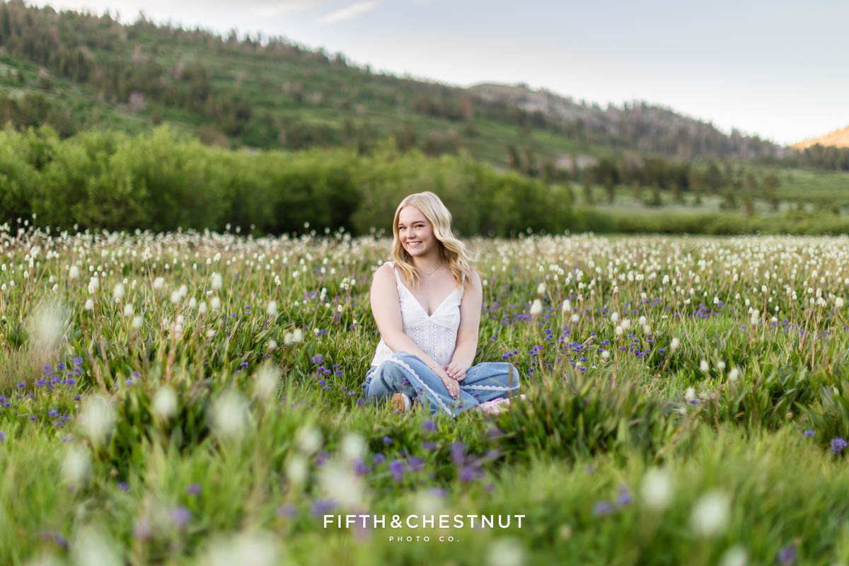 Bishop Manogue Senior sitting in a wildflower-filled meadow with a forest background
