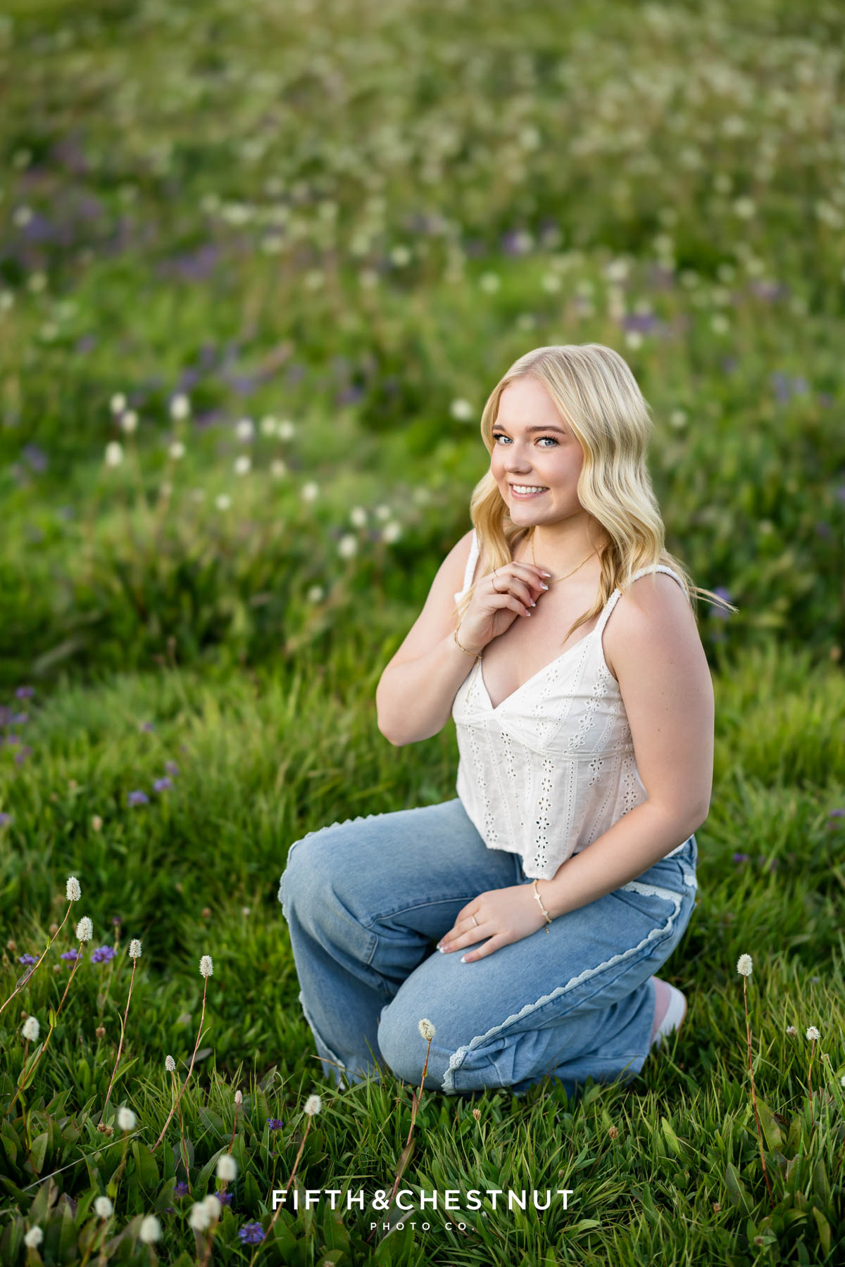 Bishop Manogue Senior sitting in a wildflower-filled meadow with a forest background