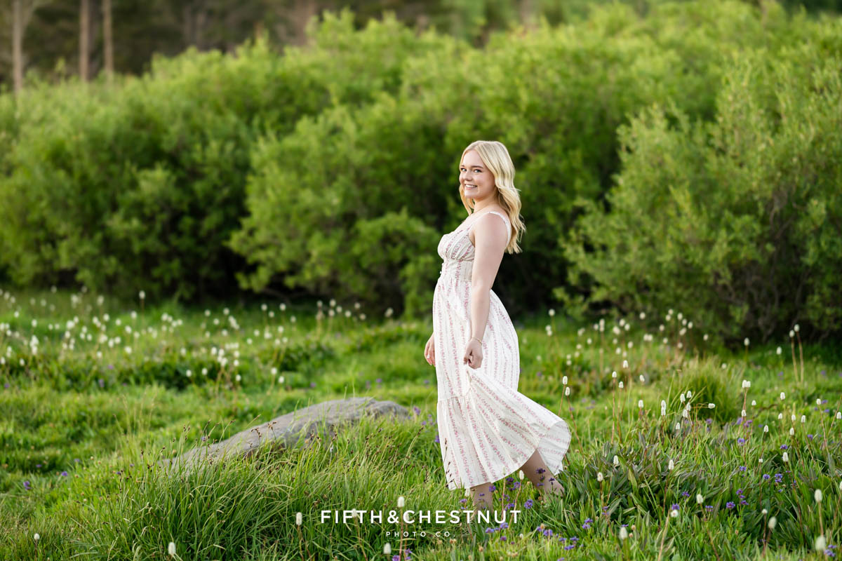 Bishop Manogue Senior walking in a wildflower-filled meadow with a forest background